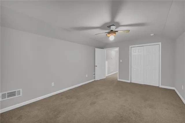 an empty room with a ceiling fan and carpet