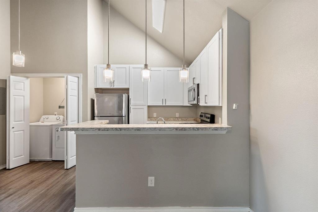 6108 Abrams Road, Unit 521 Dallas, TX 75231 - Photo 11 of 20 Kitchen featuring white cabinetry, stainless steel appliances, and a breakfast bar with a light-toned countertop