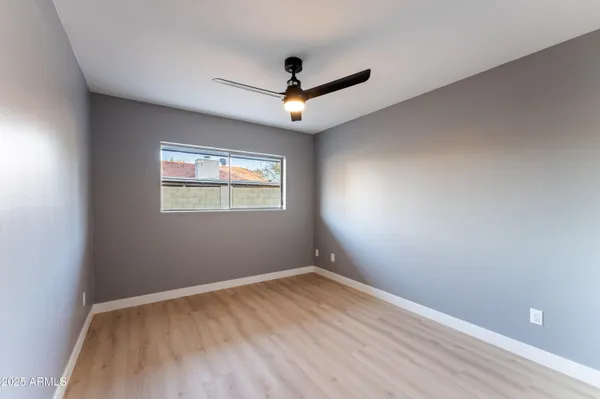 an empty room with a window and a ceiling fan