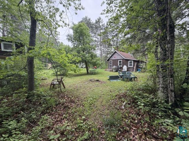 9064 Peppard Road Britt, MN 55710 - Photo 19 of 40 Wood-sided cabin with a metal roof surrounded by mature trees and a grassy clearing