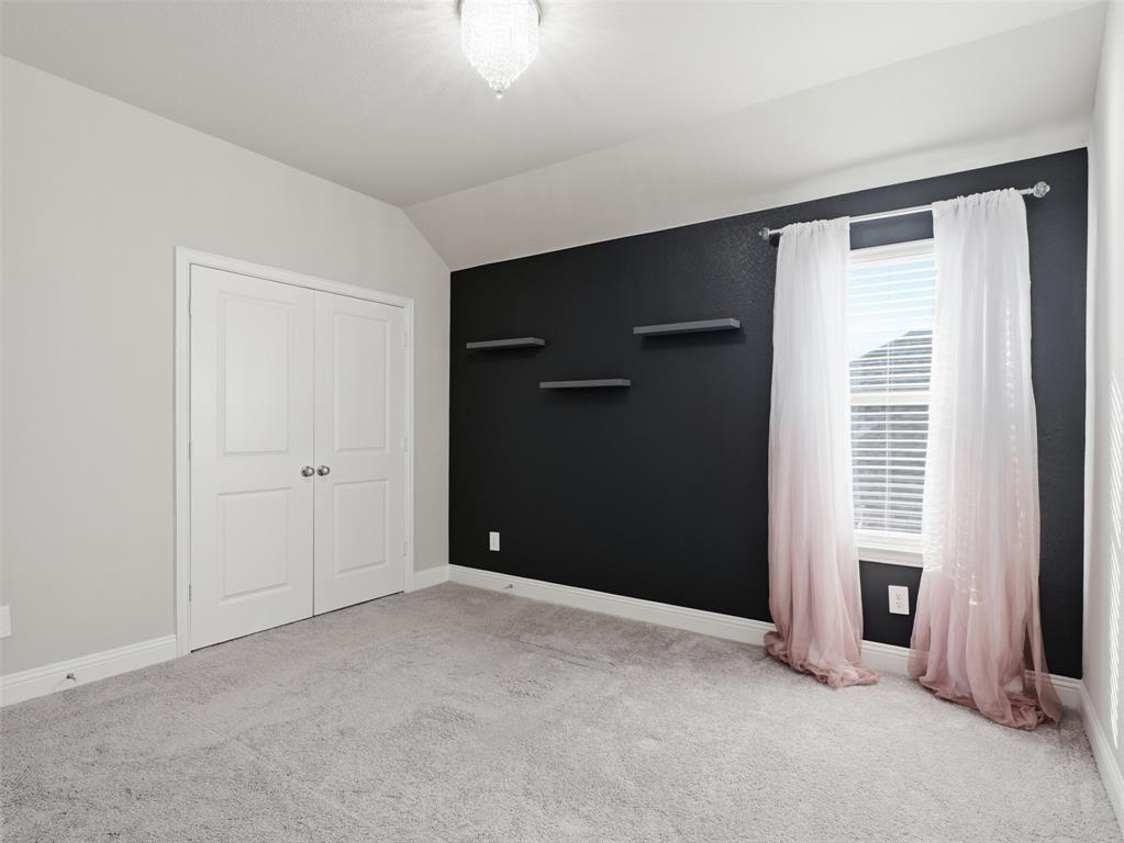 1128 Red Hawk Lane Forney, TX 75126 - Photo 25 of 37 Spacious bedroom featuring neutral carpeting, a dramatic black accent wall with floating shelves, white double-door closet, and large window with pink curtains and plantation shutters