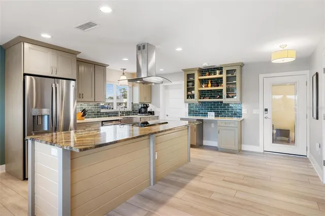 a kitchen with kitchen island granite countertop a sink stove and refrigerator