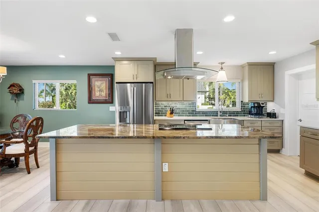a kitchen with stainless steel appliances granite countertop a stove and a view of living room