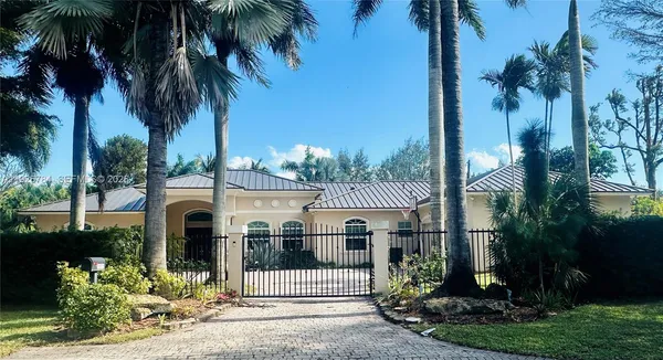 a front view of a house with a garden and palm trees