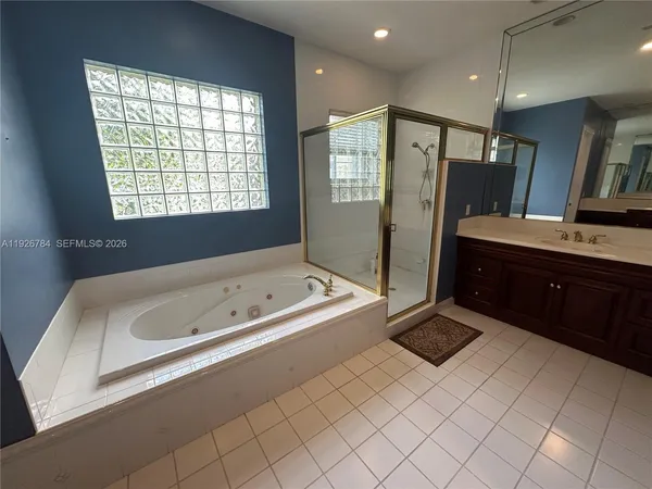 a spacious bathroom with a tub sink and mirror