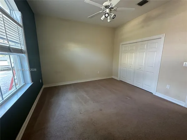 en empty room with windows and chandelier fan