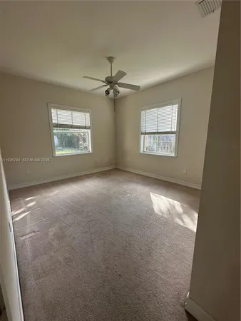 en empty room with windows and ceiling fan