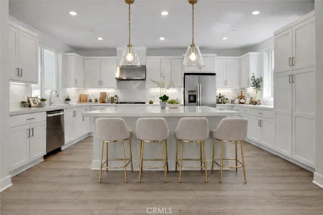 a large kitchen with cabinets chairs and wooden floor