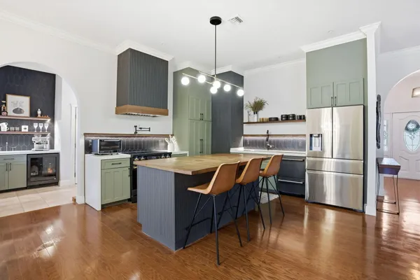 a kitchen with stainless steel appliances granite countertop a table chairs stove and refrigerator