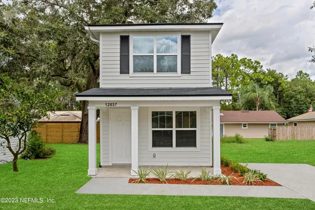 a front view of a house with a yard and potted plants