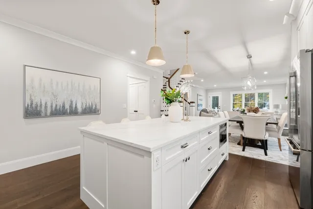 a large white kitchen with a large island oven a stove and a wooden floors