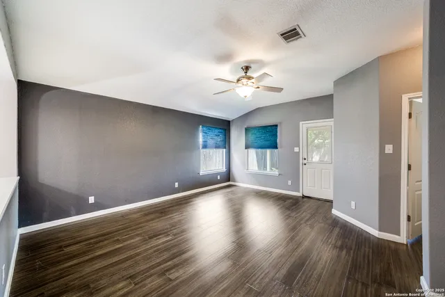 a view of an empty room with a window and wooden floor