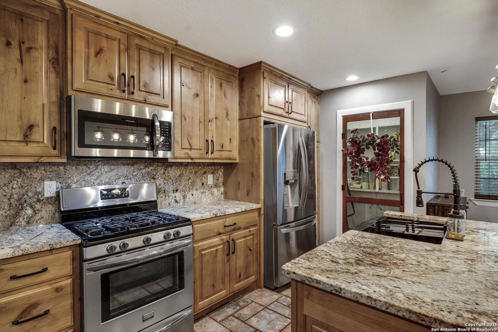10855 Jericho Road Helotes, TX 78023 - Photo 15 of 59 a kitchen with stainless steel appliances granite countertop a stove refrigerator and microwave