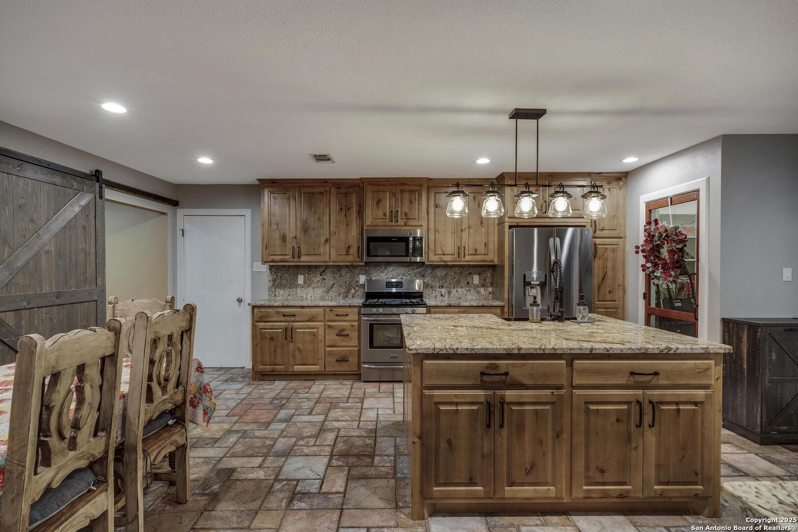 10855 Jericho Road Helotes, TX 78023 - Photo 17 of 59 a kitchen with stainless steel appliances granite countertop a sink a stove top oven a counter space and cabinets