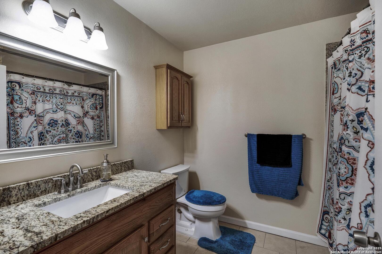 10855 Jericho Road Helotes, TX 78023 - Photo 29 of 59 a bathroom with a granite countertop toilet sink and mirror