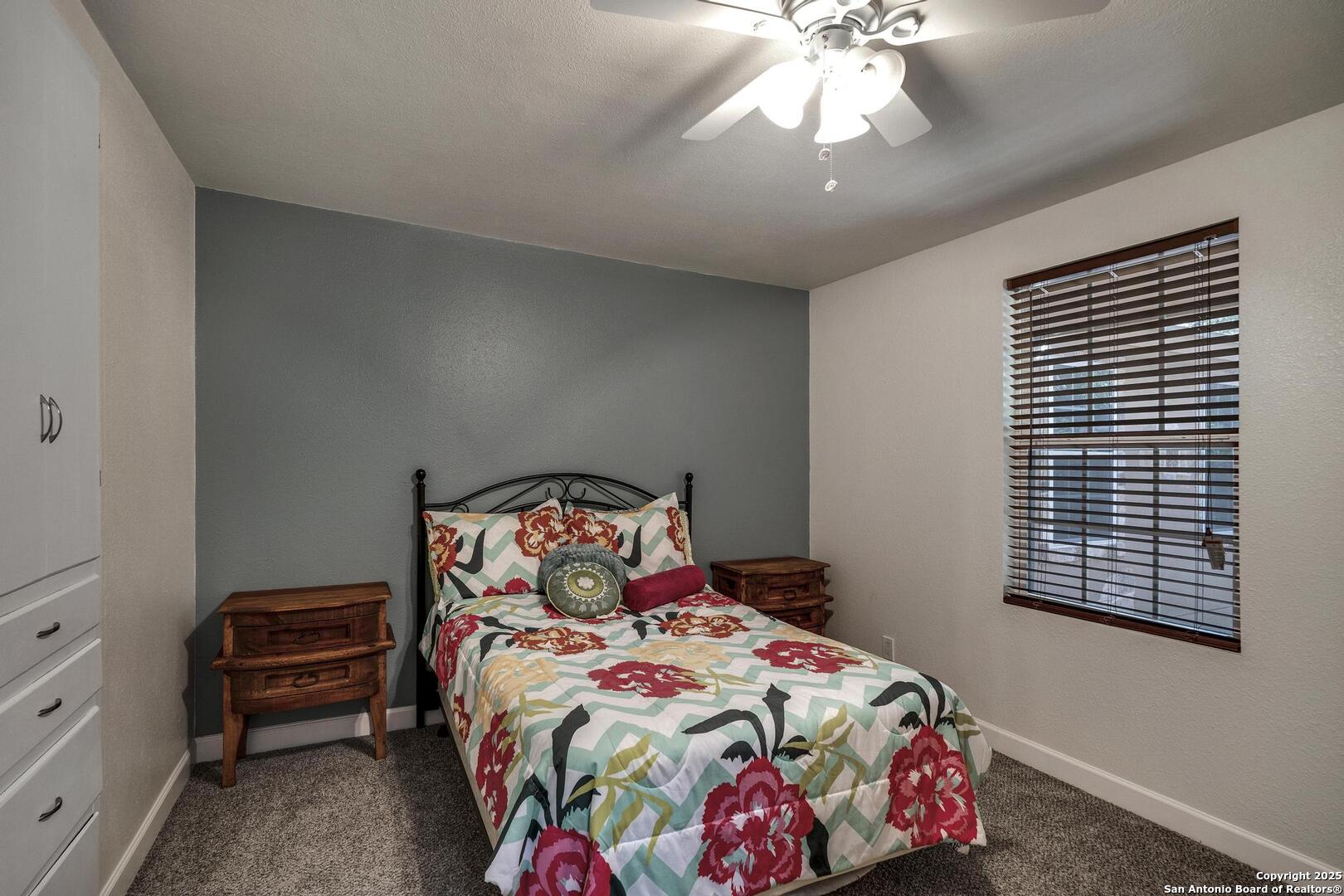 10855 Jericho Road Helotes, TX 78023 - Photo 31 of 59 a bedroom with a bed and a chandelier