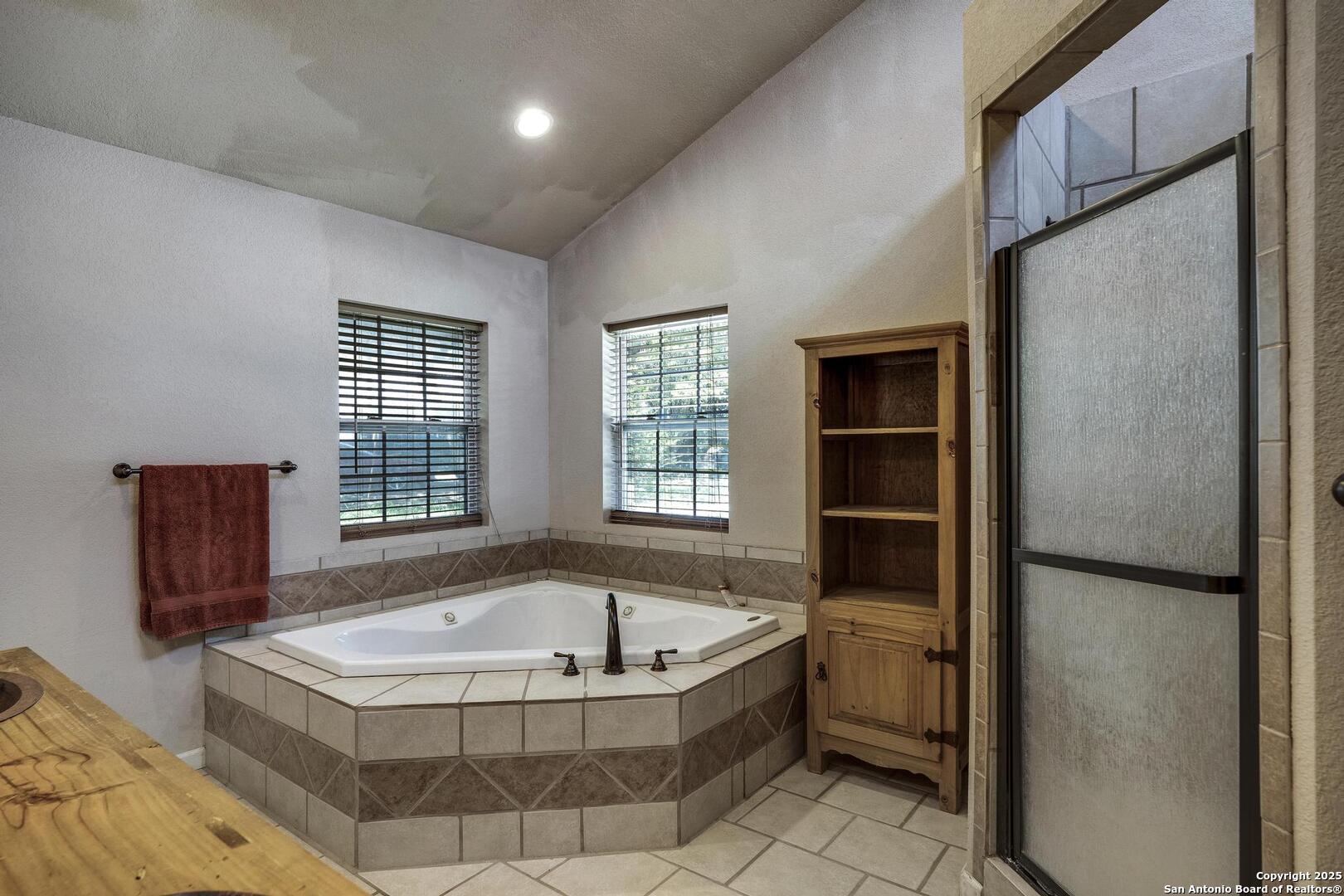10855 Jericho Road Helotes, TX 78023 - Photo 36 of 59 a bathroom with a tub a mirror and a shower