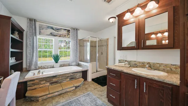a spacious bathroom with a granite countertop tub sink and mirror