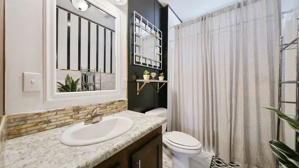 a bathroom with a granite countertop sink and a toilet