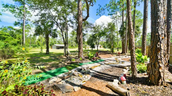 a backyard of a house with table and chairs under an umbrella