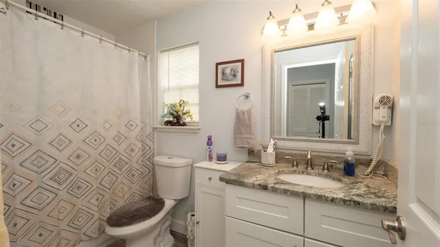 a bathroom with a granite countertop toilet sink and mirror