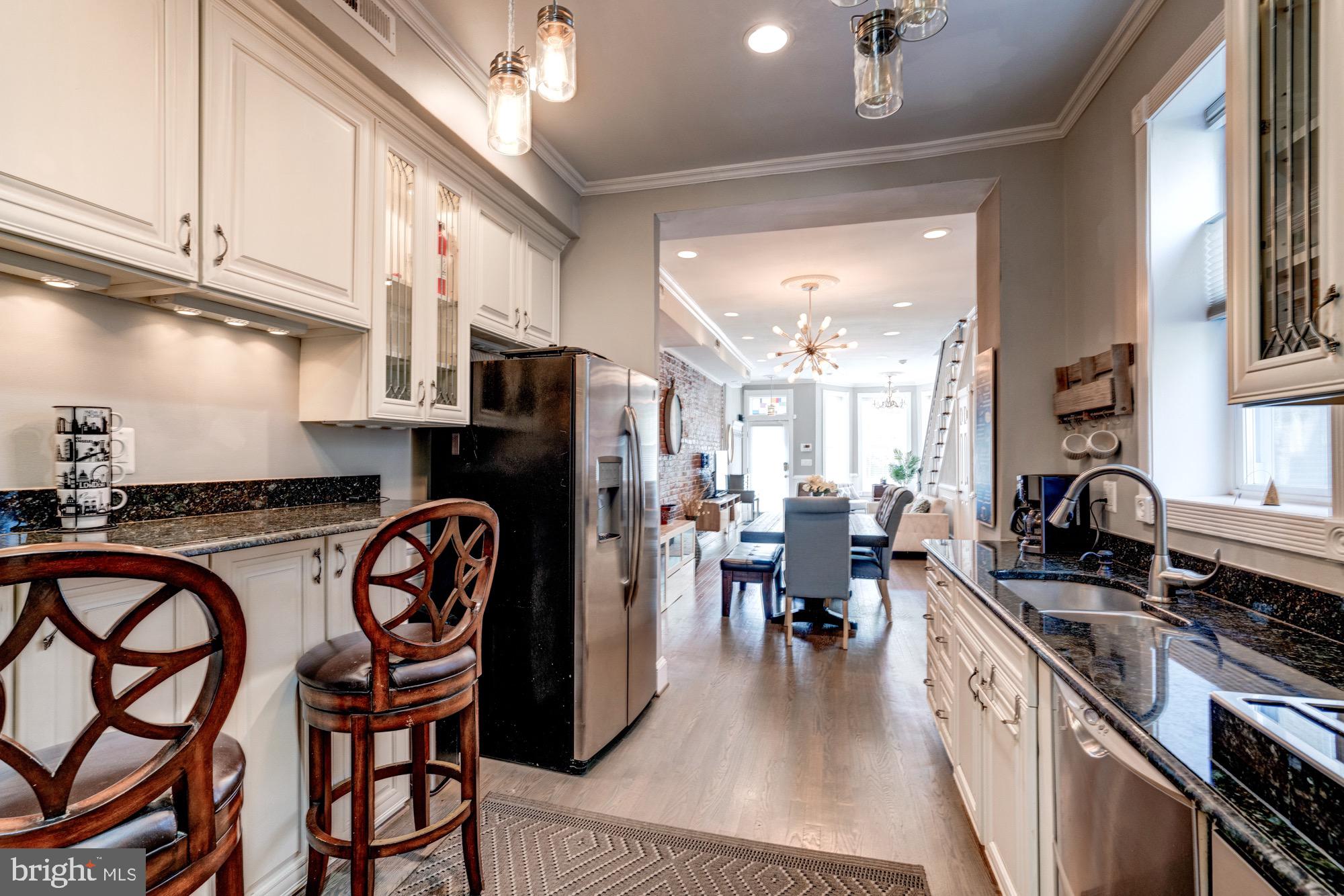 1016 G Street Southeast Washington, DC 20003 - Photo 20 of 56 a kitchen with stainless steel appliances granite countertop a stove a sink dishwasher a dining table and chairs with wooden floor