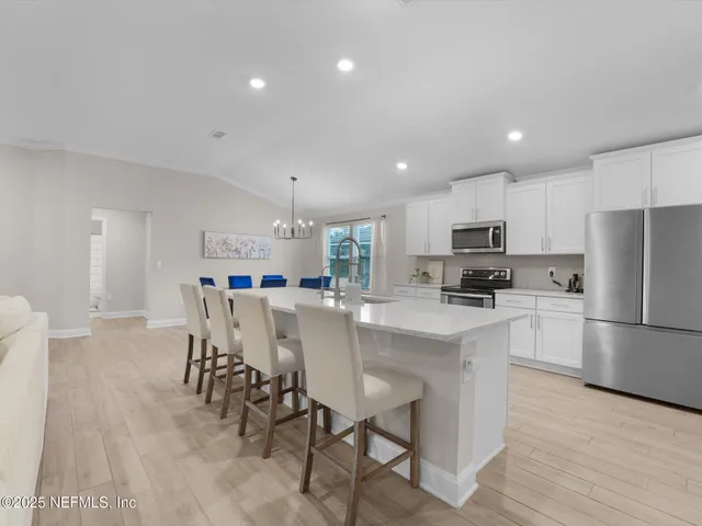 a kitchen with a dining table cabinets appliances and wooden floor