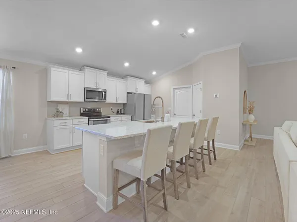 a kitchen with kitchen island a dining table chairs and white cabinets