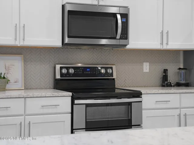 a kitchen with granite countertop white cabinets appliances and a sink