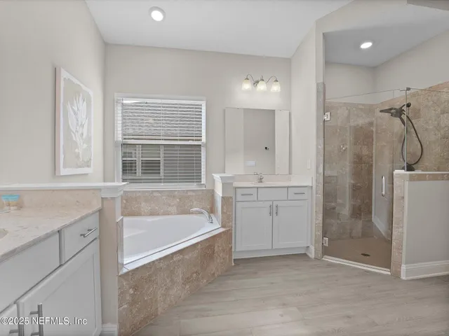 a bathroom with a tub sink shower and mirror