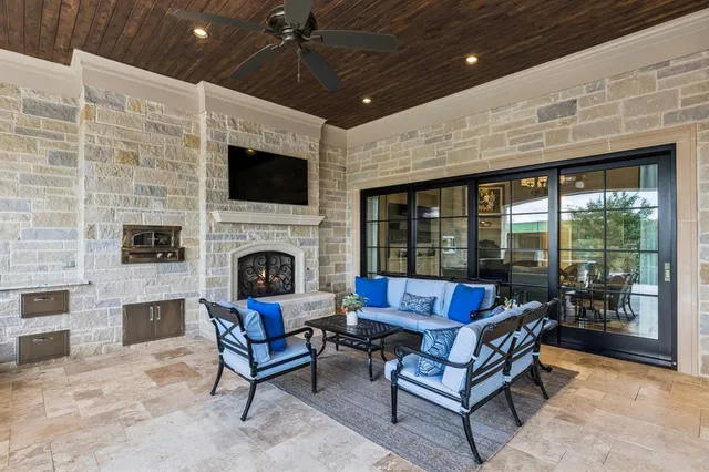 a living room with stainless steel appliances granite countertop a fireplace a flat screen tv and a fireplace