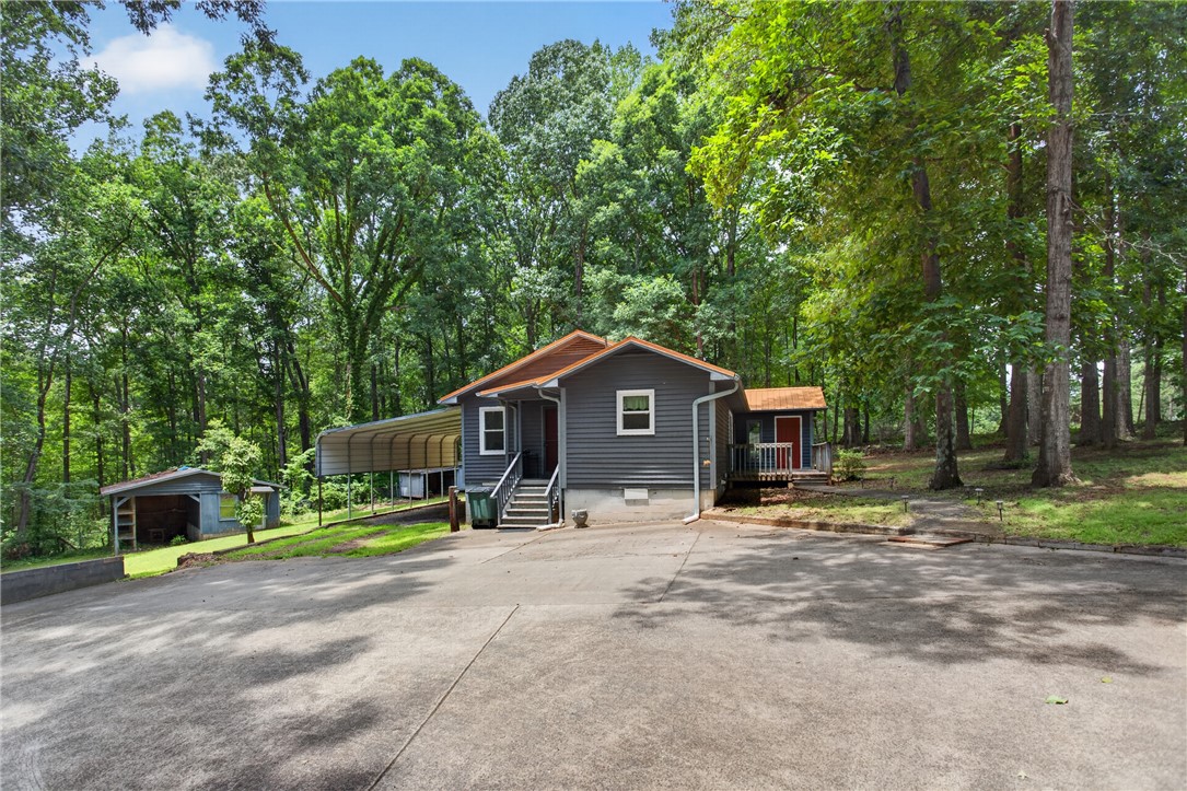 Nestled in a private wooded setting, this charming home offers a carport and additional outdoor storage.