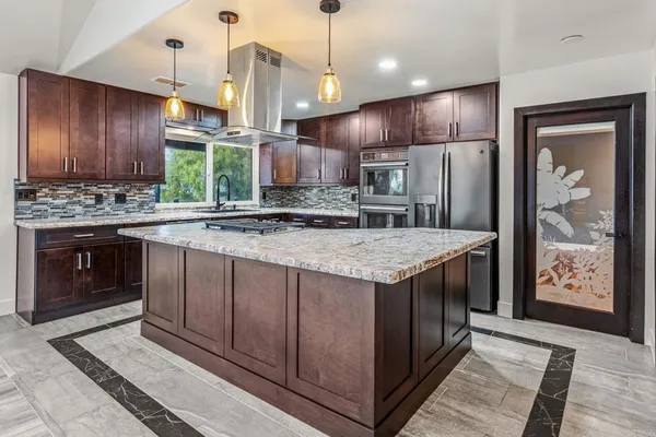 a kitchen with kitchen island granite countertop stainless steel appliances a sink stove and refrigerator