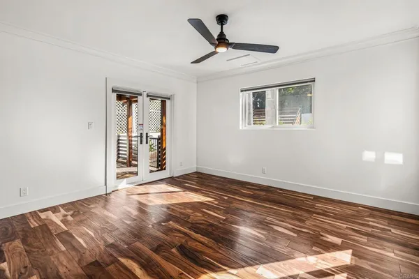 a view of empty room with wooden floor and fan