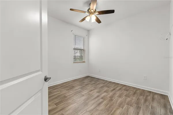an empty room with a window and ceiling fan