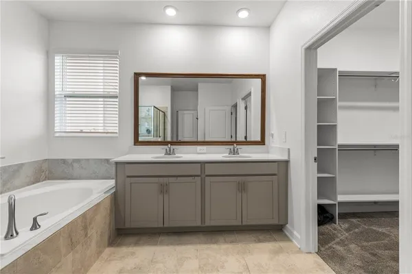 a bathroom with a granite countertop sink a mirror and a bathtub