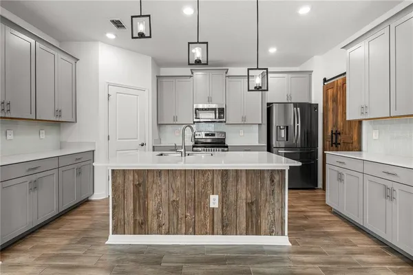 a kitchen with kitchen island stainless steel appliances a sink cabinets and wooden floor