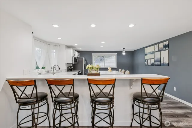a dining room with stainless steel appliances kitchen island a table and chairs in it