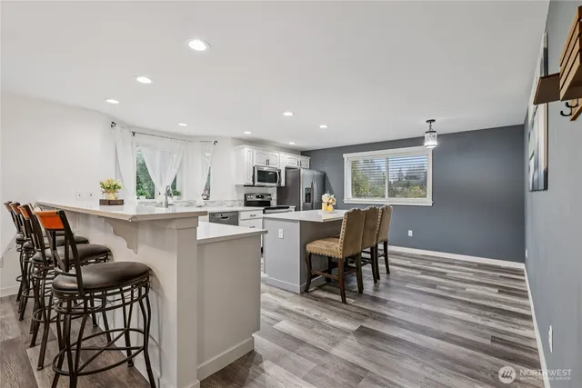 a kitchen with kitchen island a dining table chairs stainless steel appliances and cabinets