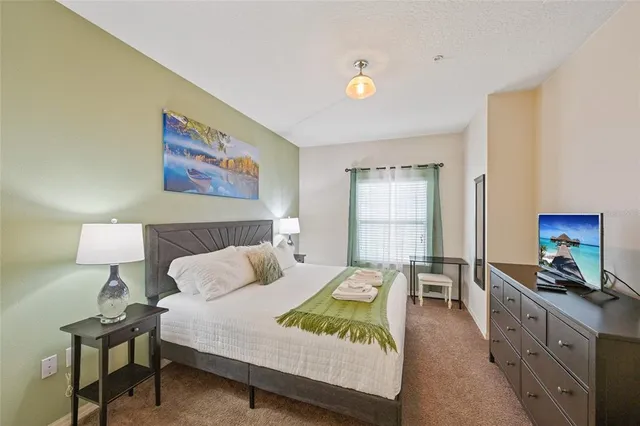 a spacious bedroom with a bed a table and painting on the wall