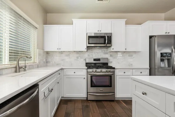 a kitchen with white cabinets and stainless steel appliances