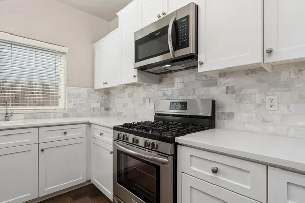 a kitchen with stainless steel appliances white cabinets and a stove top oven