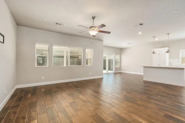 a view of an empty room with window and wooden floor