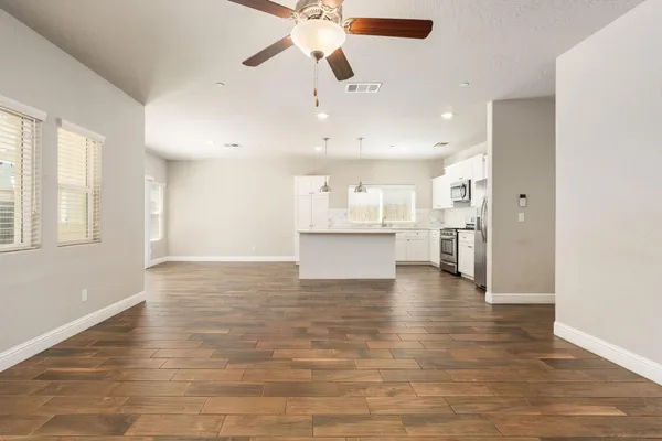 a view of an empty room with kitchen and window