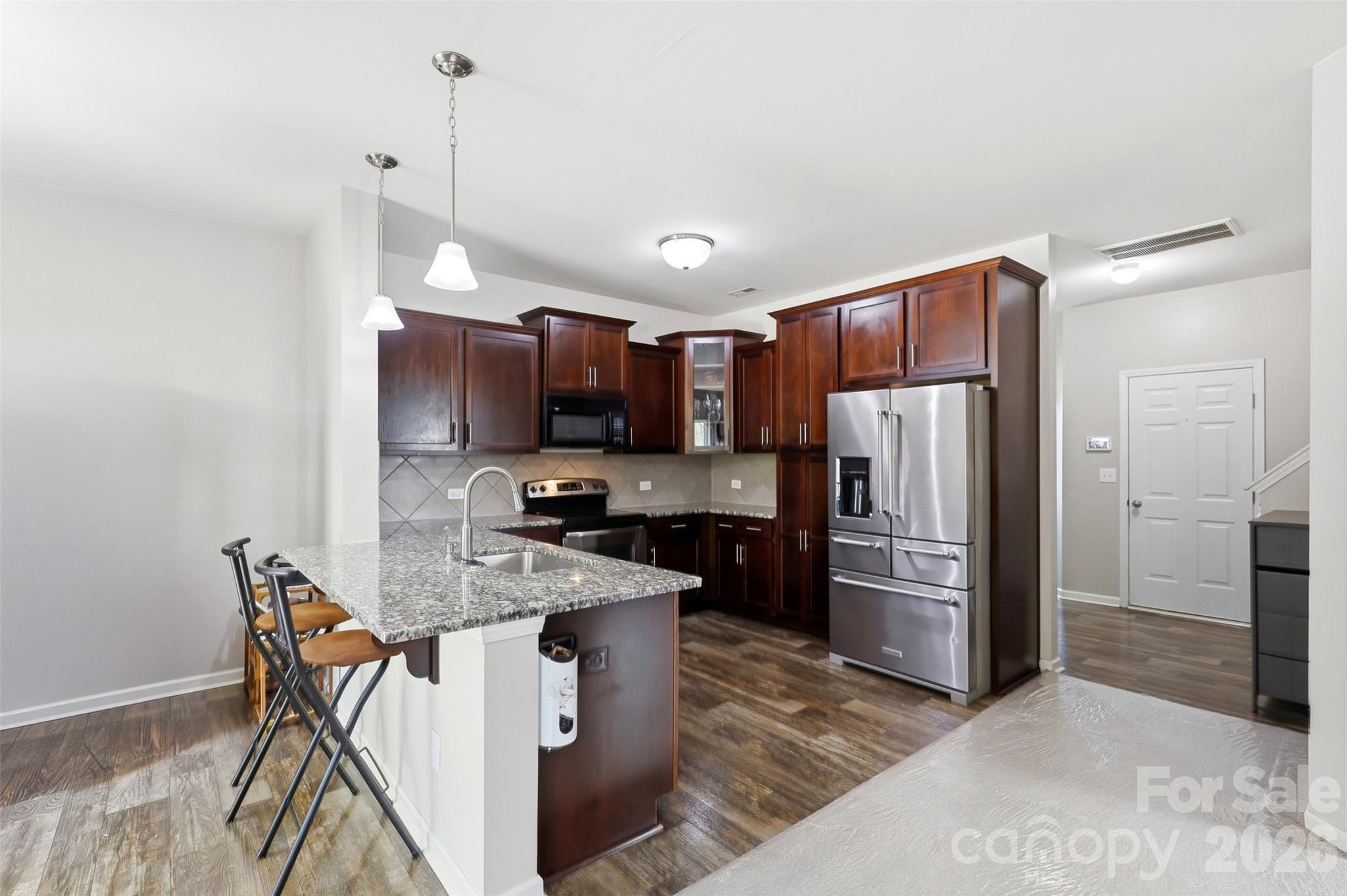 7017 Whitewater Loop Lowell, NC 28098 - Photo 5 of 39 a kitchen with stainless steel appliances granite countertop a refrigerator a stove a sink a microwave and a refrigerator