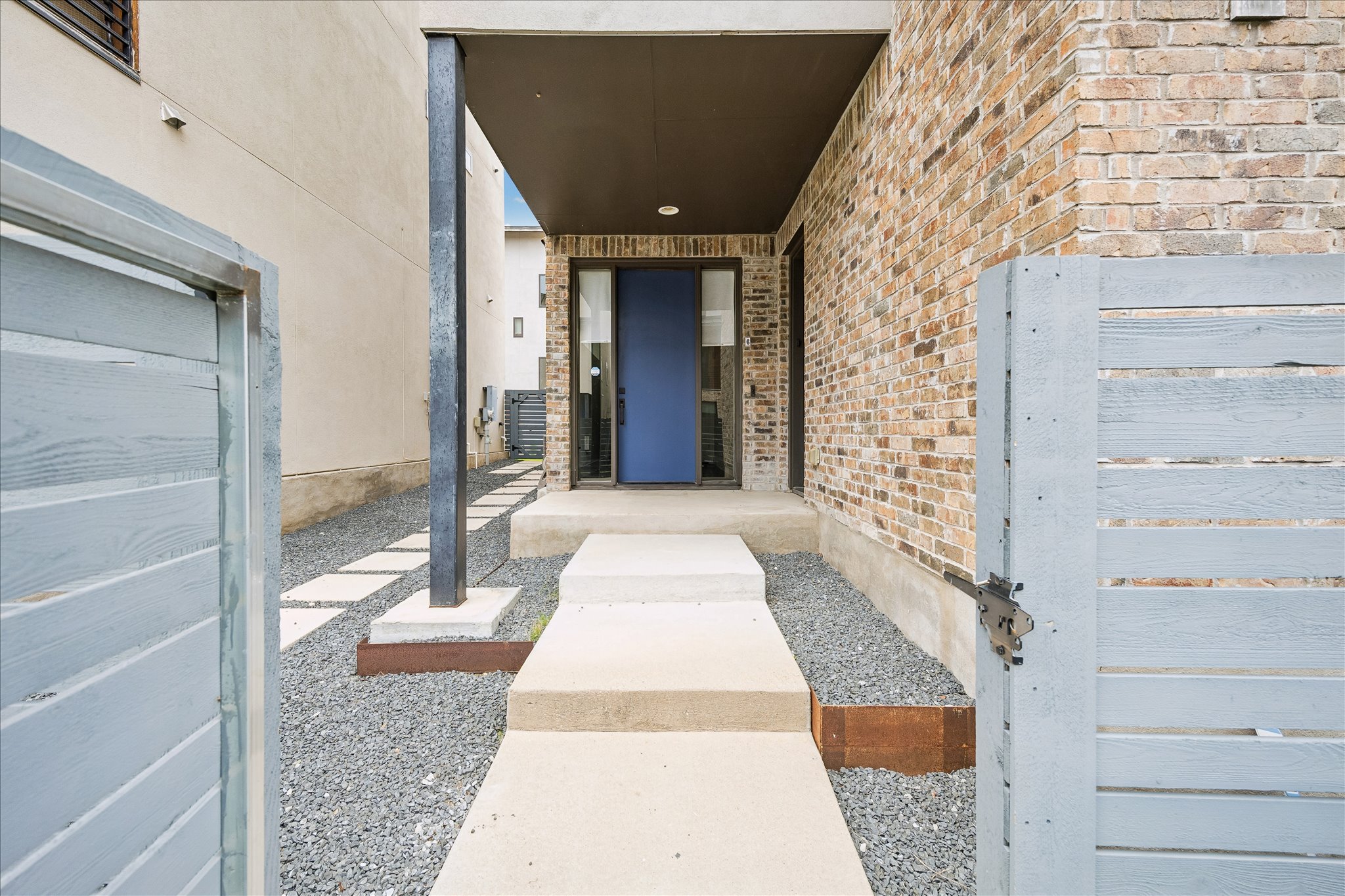 5006 Pecan Springs Road, Unit 6 Austin, TX 78723 - Photo 2 of 30 A modern entry sequence unfolds with a bold blue door, concrete steps, and a gravel pathway.