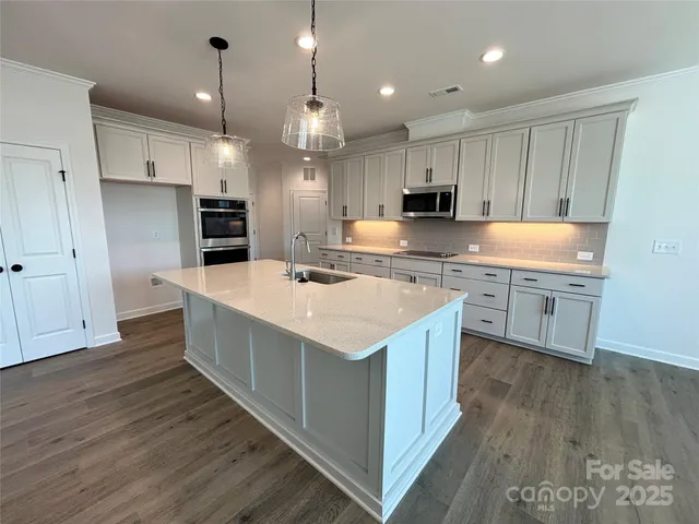 a kitchen with kitchen island granite countertop a sink appliances and cabinets
