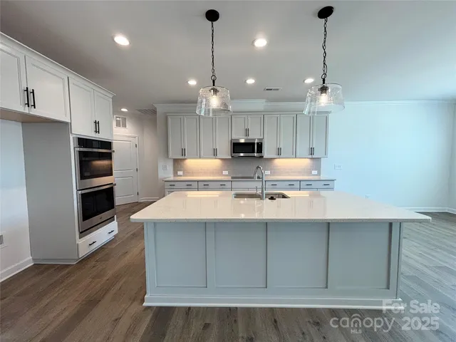 a kitchen with kitchen island a sink stainless steel appliances and wooden floor