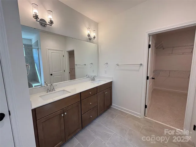 a spacious bathroom with a double vanity sink a large mirror and shower