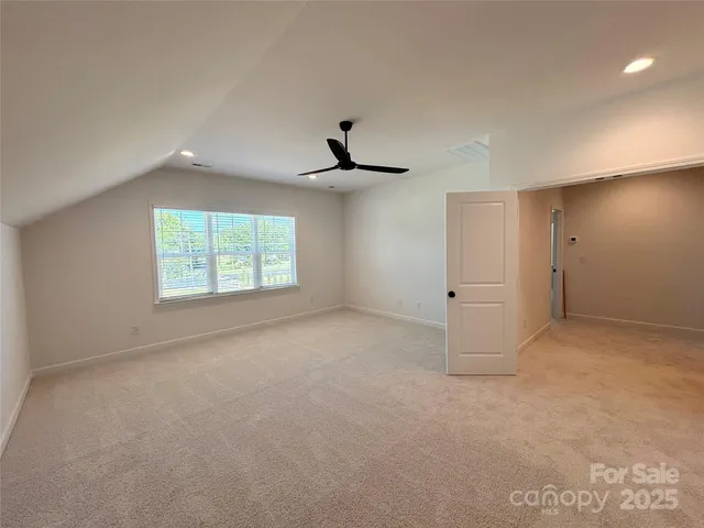 an empty room with windows and ceiling fan